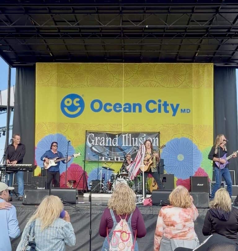 Audience watching Grand Illusion Tribute outdoor free concert at Springfest n front of an Ocean City MD stage banner