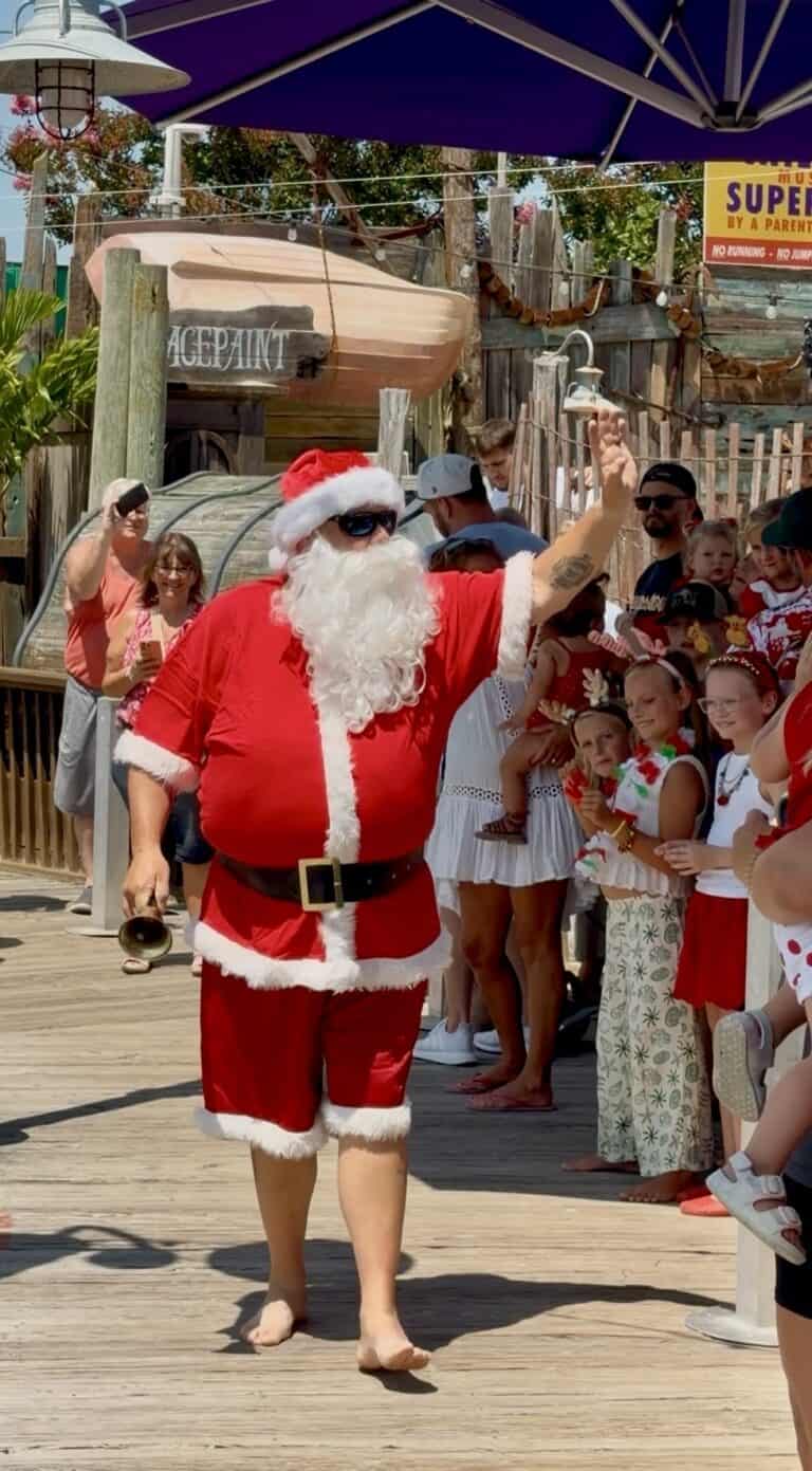 Santa waving to a crowd of kids at Fish Tales Ocean City Maryland during Christmas in July